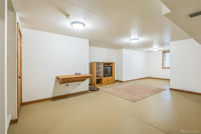 basement featuring a textured ceiling, baseboards, and visible vents