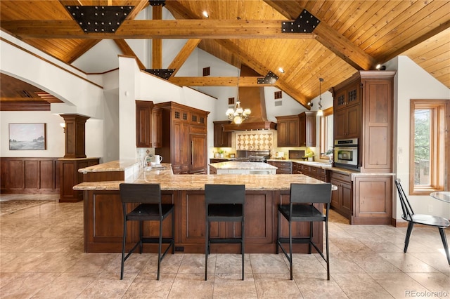 kitchen featuring light stone counters, a peninsula, oven, wooden ceiling, and a kitchen breakfast bar