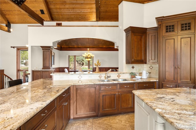 kitchen featuring wooden ceiling, lofted ceiling with beams, light stone counters, and a healthy amount of sunlight