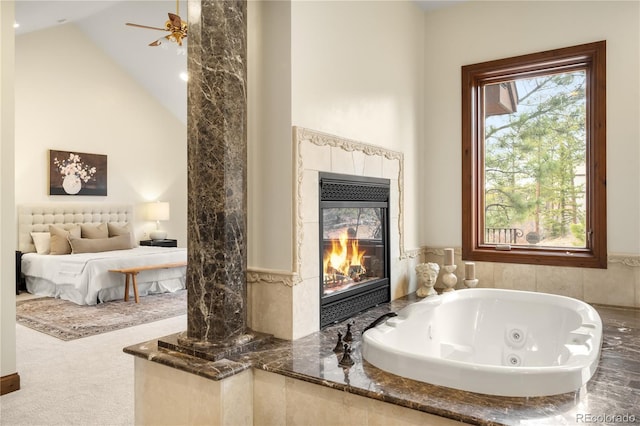 full bath with a glass covered fireplace, a jetted tub, ceiling fan, and high vaulted ceiling