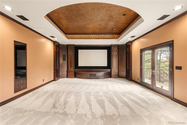 cinema with crown molding, baseboards, a tray ceiling, light carpet, and french doors