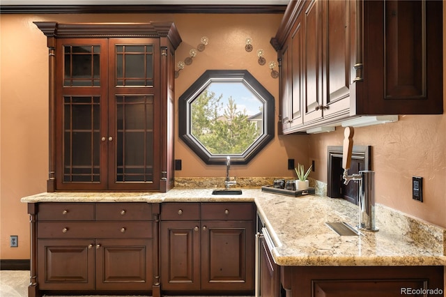 kitchen featuring a sink, glass insert cabinets, light stone countertops, and dark brown cabinetry