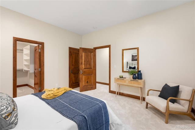 bedroom featuring baseboards, light carpet, and a spacious closet