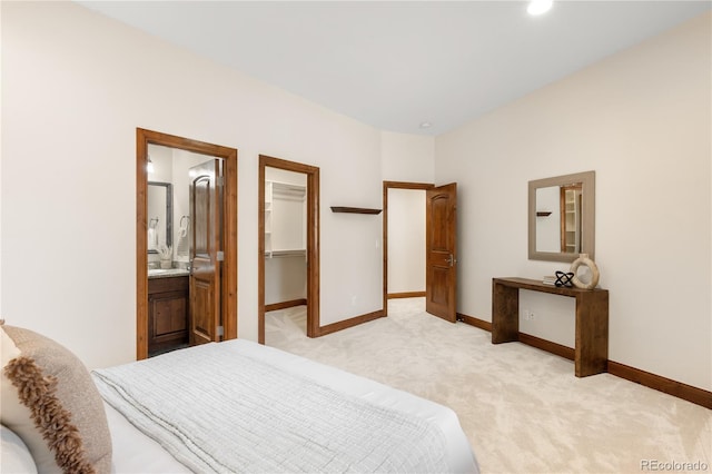 bedroom featuring baseboards, light carpet, ensuite bath, and a spacious closet