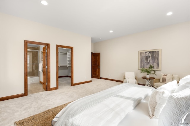 bedroom featuring light carpet, recessed lighting, a walk in closet, and baseboards