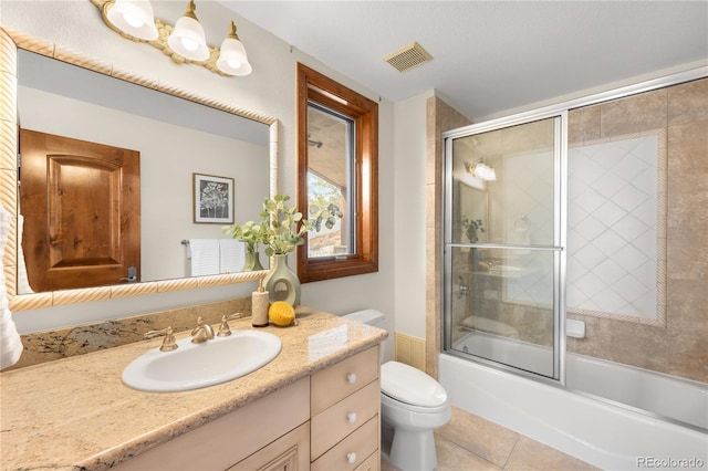 full bathroom featuring visible vents, toilet, tile patterned flooring, bath / shower combo with glass door, and vanity