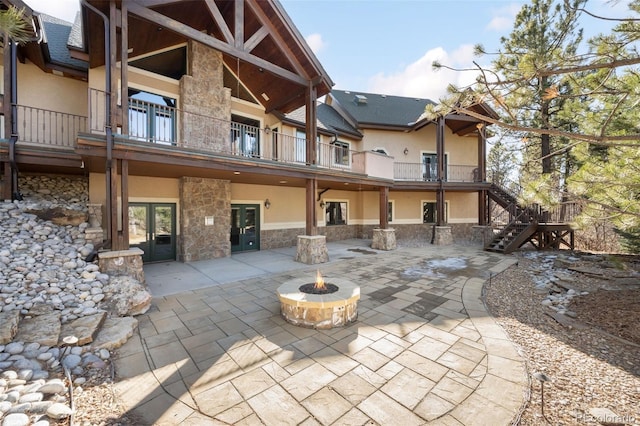 view of patio / terrace featuring french doors, a balcony, stairway, and an outdoor fire pit