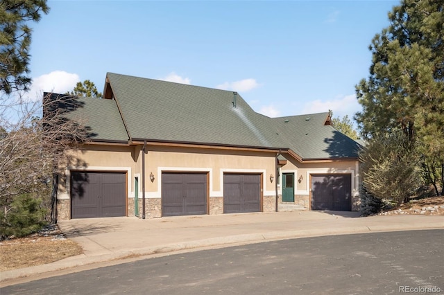 view of front of property with stucco siding, stone siding, and driveway