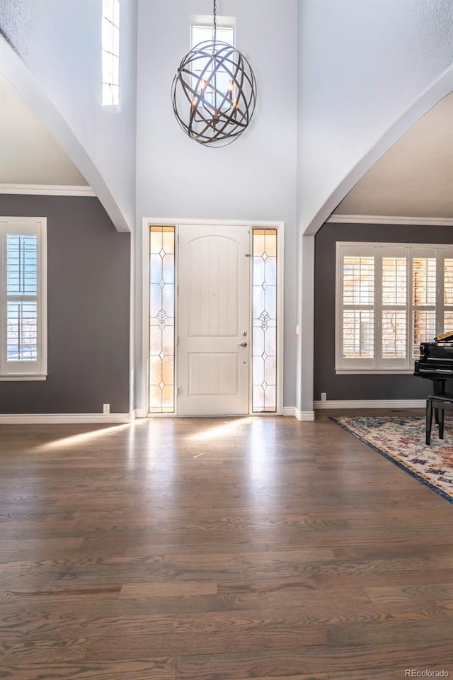 entryway with plenty of natural light, ornamental molding, and dark hardwood / wood-style floors