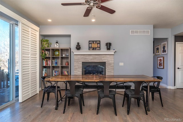 dining room featuring ceiling fan, a fireplace, and dark hardwood / wood-style floors