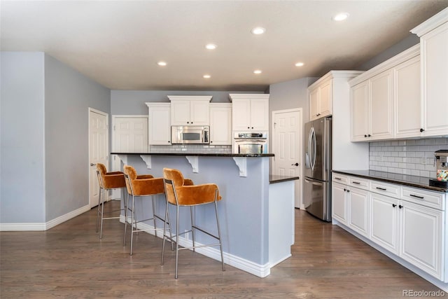 kitchen with white cabinetry, appliances with stainless steel finishes, dark hardwood / wood-style floors, and a center island