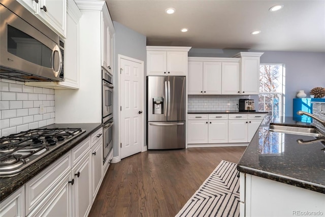 kitchen with white cabinetry, sink, dark hardwood / wood-style flooring, dark stone counters, and stainless steel appliances