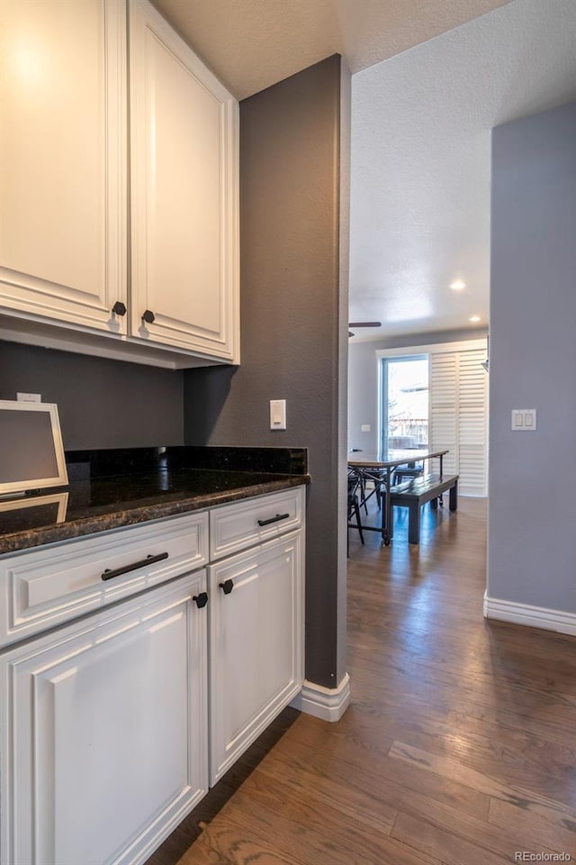 kitchen featuring white cabinetry, dark hardwood / wood-style flooring, and dark stone counters