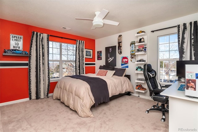 bedroom with ceiling fan, multiple windows, and light carpet