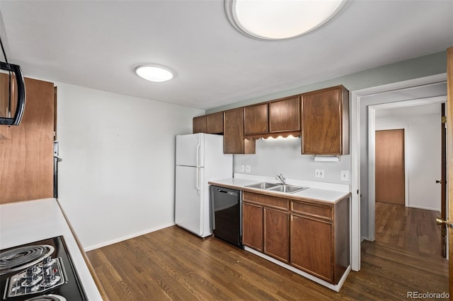 kitchen featuring dark wood-style flooring, a sink, black dishwasher, light countertops, and freestanding refrigerator