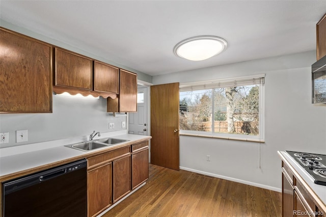 kitchen with black dishwasher, baseboards, dark wood-type flooring, light countertops, and a sink