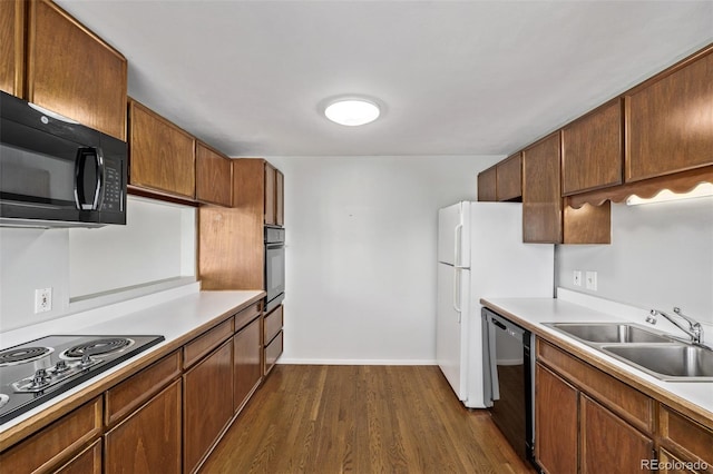 kitchen featuring dark wood finished floors, light countertops, a sink, and black appliances