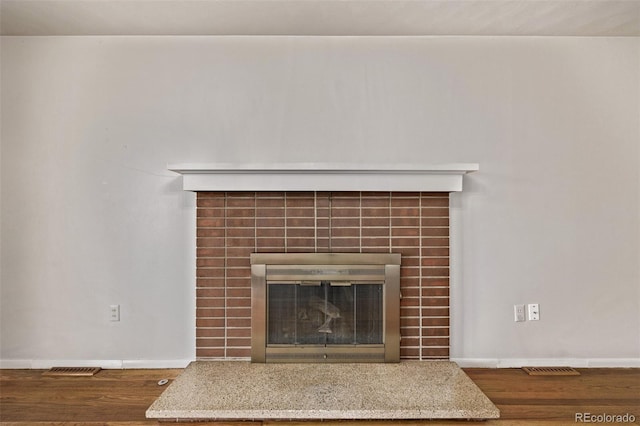 room details featuring a fireplace, wood finished floors, visible vents, and baseboards