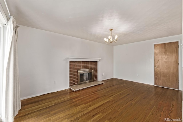 unfurnished living room featuring a notable chandelier, a fireplace, and wood finished floors