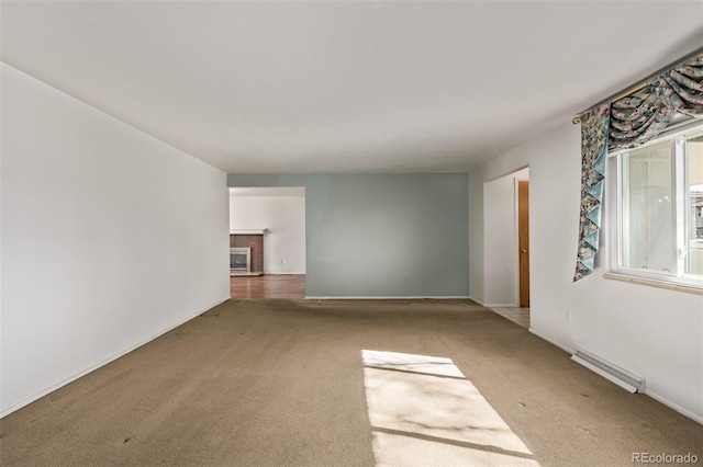 unfurnished living room with a brick fireplace, visible vents, and carpet flooring