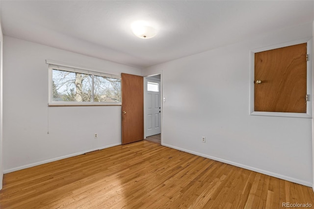 spare room featuring light wood-style floors and baseboards