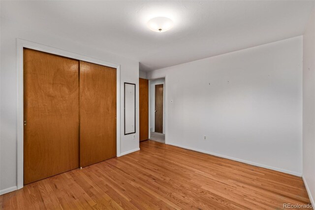 unfurnished bedroom with a closet, wood finished floors, and baseboards