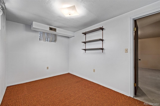 carpeted empty room featuring visible vents, a textured ceiling, and baseboards