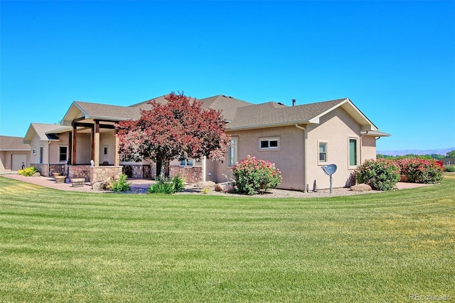 back of property featuring roof with shingles, a lawn, and stucco siding