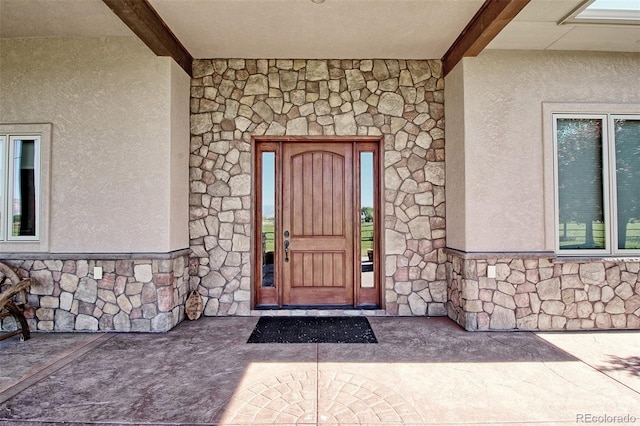 property entrance with stucco siding and stone siding