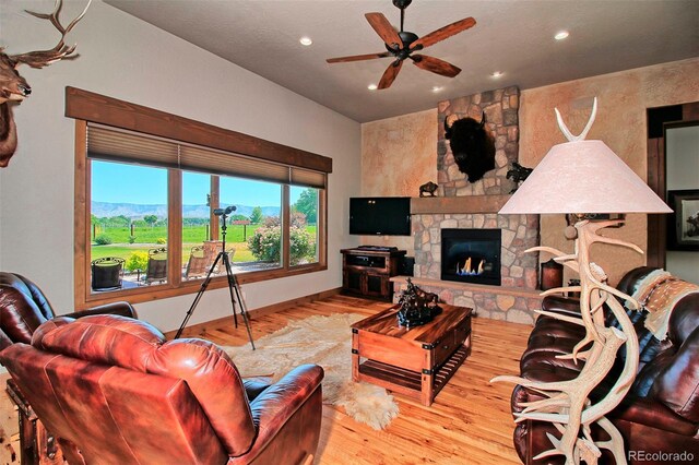 living area featuring recessed lighting, a stone fireplace, a ceiling fan, and wood finished floors