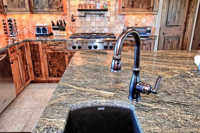 details featuring dark stone countertops, tasteful backsplash, a sink, and stainless steel appliances