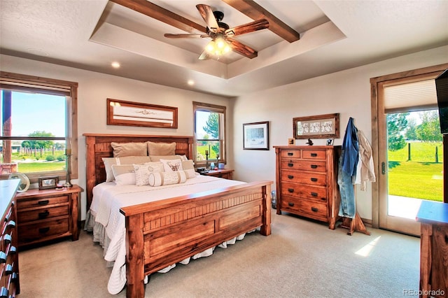 bedroom with access to exterior, a tray ceiling, light colored carpet, and a ceiling fan