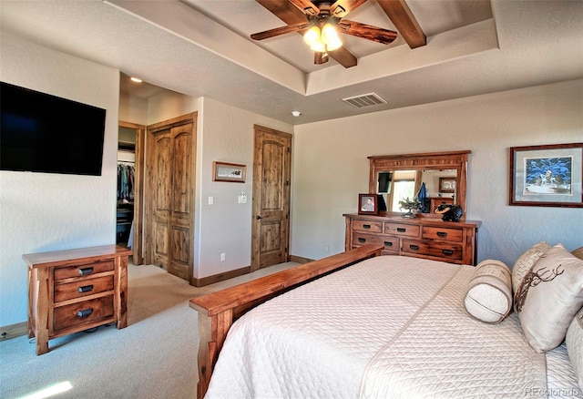 bedroom with baseboards, carpet floors, visible vents, a tray ceiling, and ceiling fan