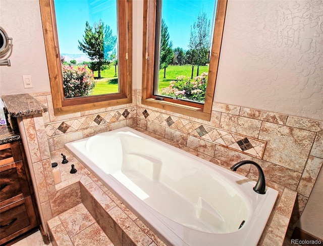 bathroom featuring a textured wall and a garden tub