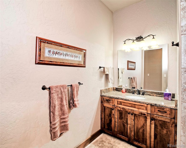 bathroom featuring baseboards, vanity, and a textured wall