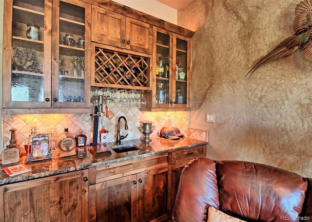 bar featuring tasteful backsplash, wet bar, a sink, and a textured wall