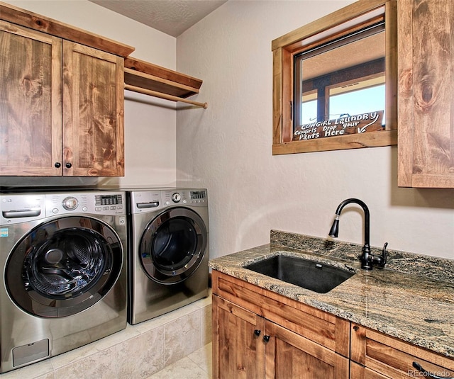 laundry room with washing machine and dryer, a textured ceiling, a sink, and cabinet space
