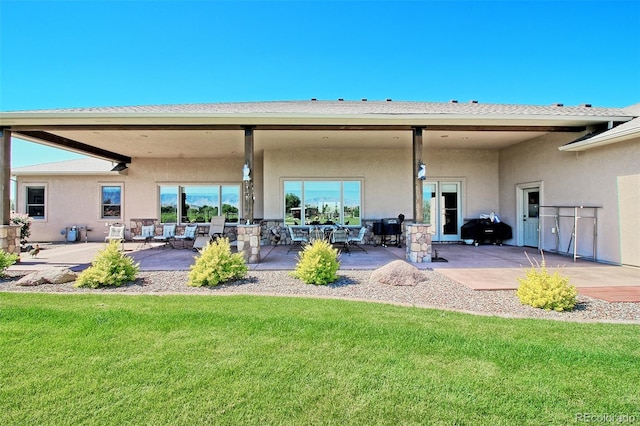 rear view of property with a patio, stucco siding, and a lawn