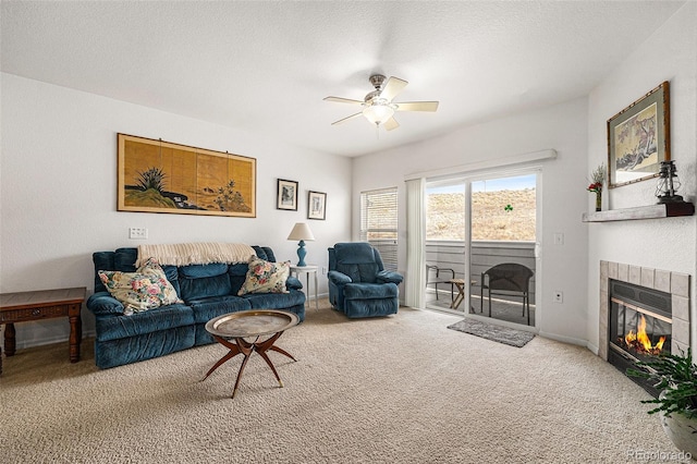 living area featuring baseboards, ceiling fan, a textured ceiling, carpet flooring, and a fireplace