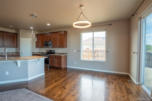 1985 Reed Grass Way, Colorado Springs, CO 80915 - kitchen featuring appliances with stainless steel finishes, dark wood-style floors, a breakfast bar, hanging light fixtures, and recessed lighting