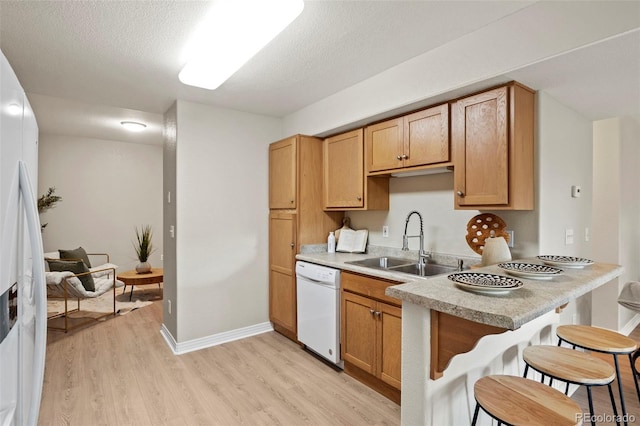 4109 Sunny Vista Hts, Colorado Springs, CO 80918 - kitchen featuring white appliances, light wood-style floors, a kitchen breakfast bar, light countertops, and a textured ceiling
