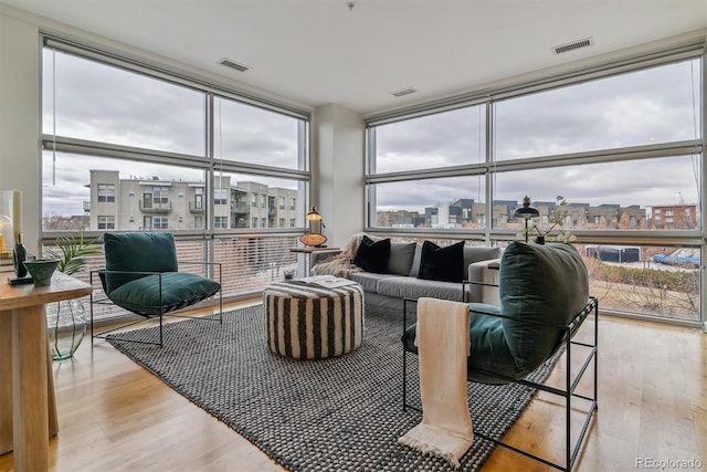 living room with light hardwood / wood-style floors and a wall of windows