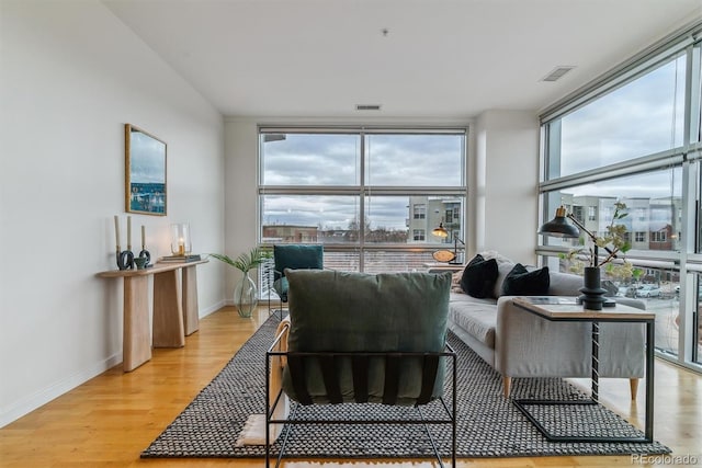 living room featuring a wall of windows and light hardwood / wood-style flooring