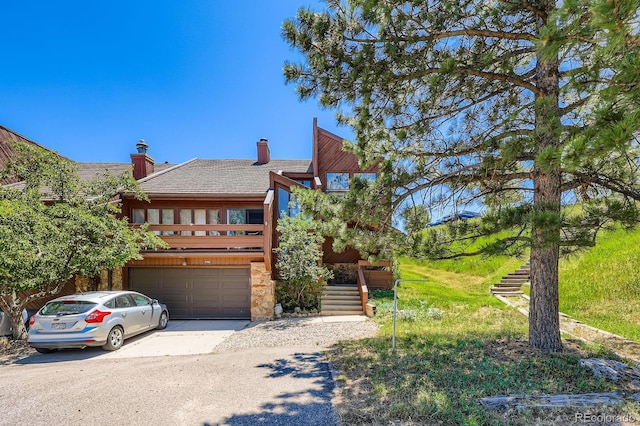 4484 Juniper Ct, Larkspur, CO 80118 - view of front of home featuring driveway, an attached garage, stone siding, stairway, and a chimney