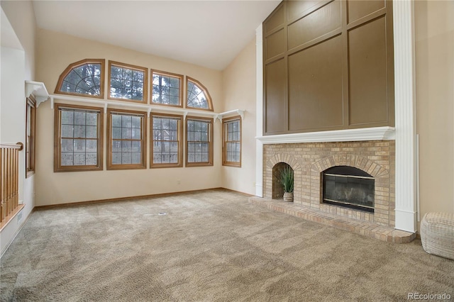 unfurnished living room with a brick fireplace, light carpet, and high vaulted ceiling