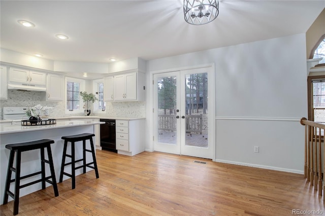 kitchen featuring black dishwasher, white cabinets, decorative backsplash, light hardwood / wood-style floors, and french doors