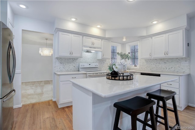 kitchen with hanging light fixtures, white cabinetry, electric range, and stainless steel refrigerator