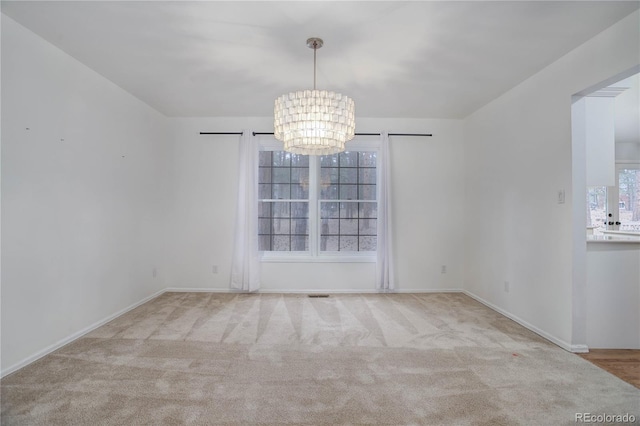 carpeted empty room featuring a notable chandelier