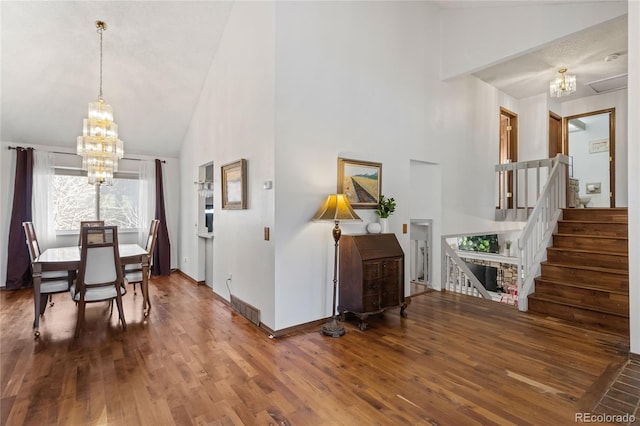 dining area featuring hardwood / wood-style floors, a notable chandelier, and high vaulted ceiling