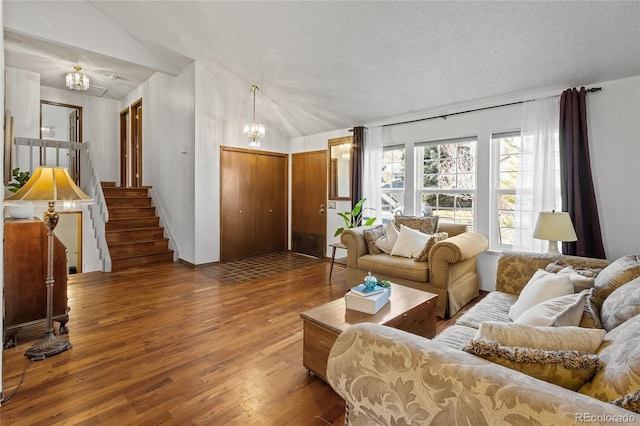 living room featuring dark hardwood / wood-style floors, a chandelier, vaulted ceiling, and a textured ceiling